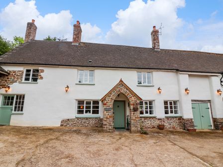 The exterior of a white stone cottage with green doors and windows at Fishermen's Cottage in Chawleigh near Chulmleigh