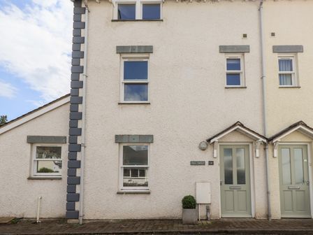 The front of a white two story house with four windows two pale green doors and a small planter by the door at Fell Sweep in Keswick