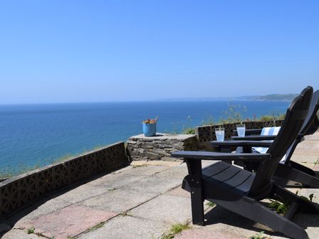 A patio with black chairs and glasses overlooking the ocean at Westcroft 6 Withnoe Terrace in Millbrook near Whitsand Bay