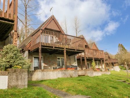 A row of houses with wooden balconies and sloped roofs overlooking a grassy area at No 51 Valley Lodges in Honicombe Manor near Gunnislake