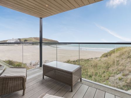 A balcony with wicker furniture overlooking a sandy beach and grassy dunes at Apartment 18 Burgh Island Causeway Bigbury-On-Sea