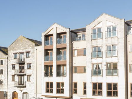 An exterior view of a multi-story residential building with balconies and large windows at Townbridge Apartment in Weymouth