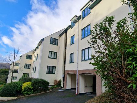 A residential building with multiple windows and greenery in front at Bowness Hideaway in Bowness-On-Windermere