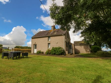 A house with a lawn and outdoor chairs under a tree at Garreg Lwyd Farm Morfa Nefyn near Nefyn