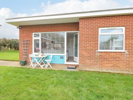 Exterior of a brick building with a small white table and two chairs on a patio at 12 Siesta Mar in Mundesley