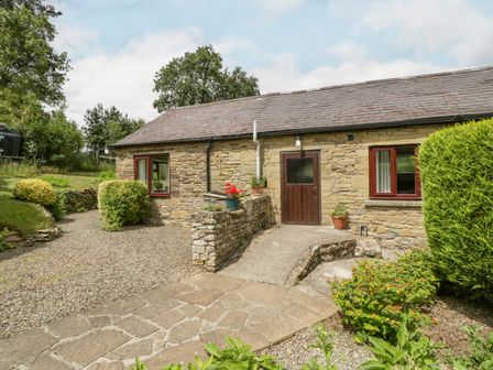 A stone cottage with a tiled roof and wooden door surrounded by a gravel path and garden at Fieldfare in Kingsland