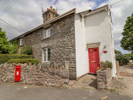 A stone and white plaster house with a red door and mailbox at The Old Post Office in Llanelian near Old Colwyn