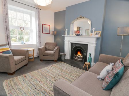 A living room with armchairs a sofa a fireplace and a window at Swn Yr Afon in Abergynolwyn near Tywyn