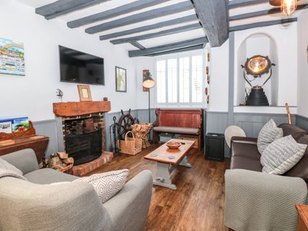 A living room with a fireplace a mounted TV two sofas a wooden coffee table and a wooden bench at Dancing Beggars in Dartmouth