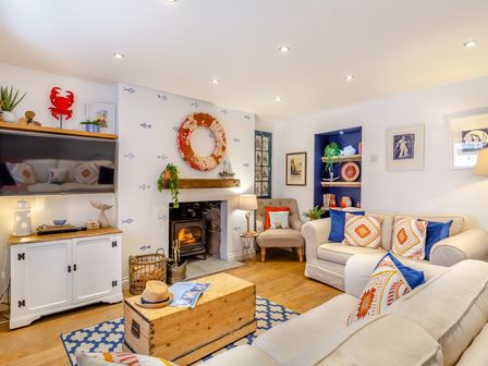 A living room with a fireplace a TV sofas and a wooden chest at Pentreath in Kingsand