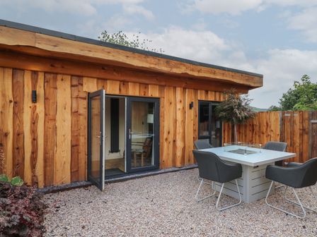 An outdoor patio area with a wooden fence and a dining table with four chairs at Daffodil in Llangadfan