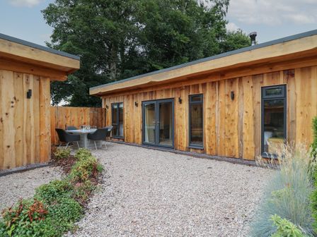 A wooden cabin with gravel courtyard and outdoor dining set at Rhosyn in Llangadfan