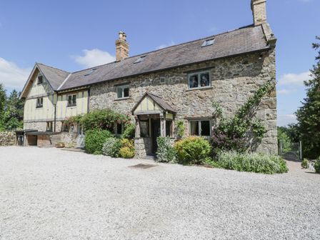 A stone and timber house with a gravel driveway and garden at Pentre Hall in Bronygarth near Chirk