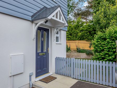 Exterior front door of a house with a small porch canopy and a blue picket fence at 6 Chatterton Mews Lyme Regis