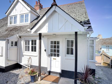 Front entrance of a white house with a door, windows, two black pillars, and potted plants at Waverley Lyme Regis