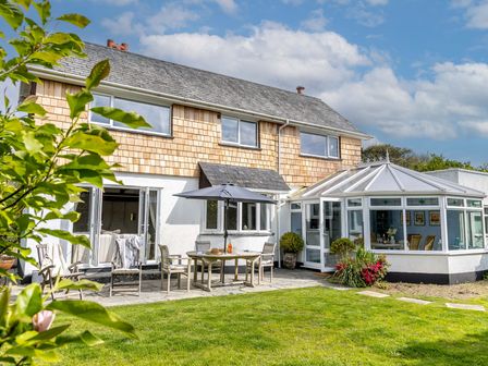 A garden view of a house with a patio and conservatory at 7 Duporth Bay in St. Austell
