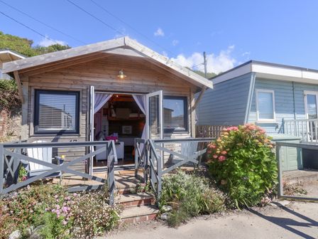 A wooden cabin with open doors and a small garden in front at Sea Spray in Lyme Regis