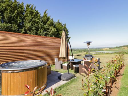 An outdoor area with a wooden hot tub patio furniture and a patio heater at Ailsa Craig in Hillhampton Great Witley