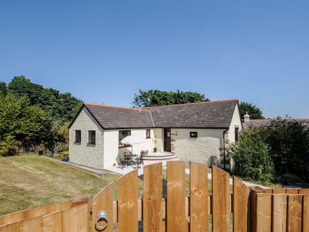 A white stone house with a slate roof behind a wooden fence in a garden at No 1 in Pensilva Near Liskeard