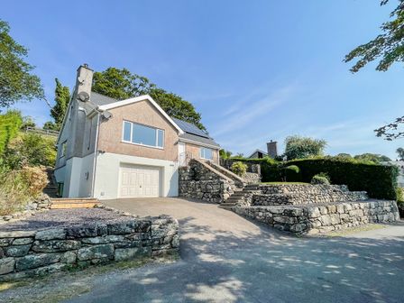 A house with a garage and stone retaining walls along a driveway at Lleifior in Dolgellau