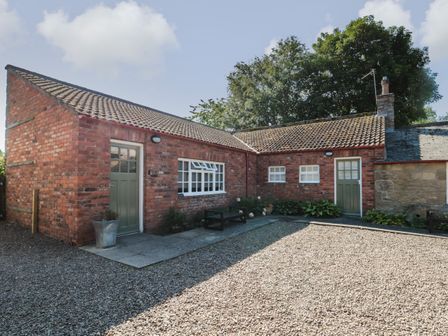 A brick building with two green doors and a gravel courtyard at Silverbirch in Crookham near Cornhill-On-Tweed