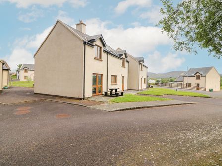 Residential houses with beige walls and grey roofs on a paved road with grass areas at 14 Sneem Leisure Village in Sneem County Kerry