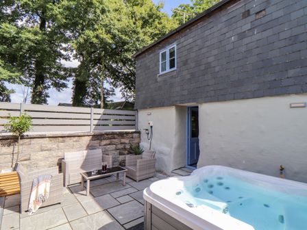 An outdoor patio with seating furniture and a hot tub next to a building at St Keverne in Mawnan Smith Near Falmouth