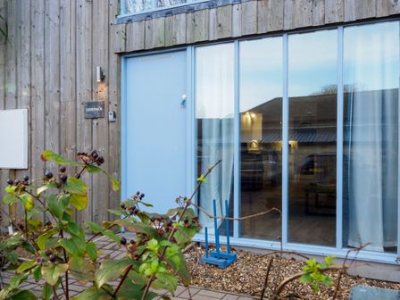 A wooden exterior with a blue door and large windows at Coverack in Mawnan Smith Near Falmouth
