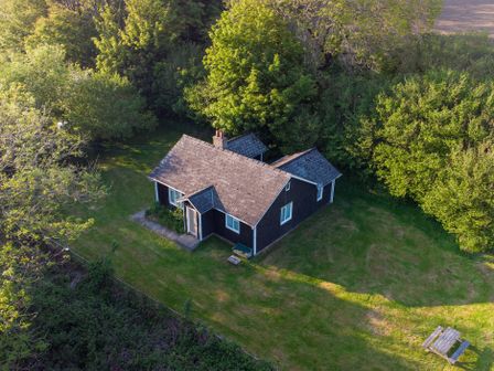 A small house surrounded by trees and grass with a picnic table nearby at Henllys Lodge in Newport Pembrokeshire