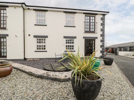Exterior view of a building with gravel yard and planters with plants at Whistle Stop Apartment in Porthmadog