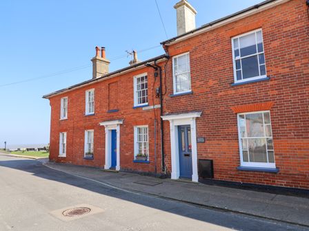 A street view of red brick houses with blue doors and white window frames in Southwold