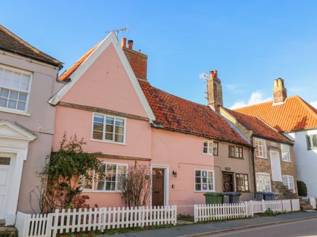 A row of houses with red tiled roofs and a white picket fence at Lavender Cottage in Aldeburgh