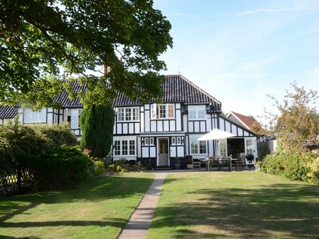 A black and white timber framed house with a tiled roof and garden furniture on a patio at 2 The Bays Thorpeness