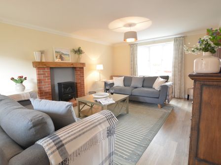 A living room with gray sofas a coffee table and a brick fireplace at Meadowsweet Blythburgh near Reydon