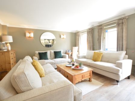 A living room with beige sofas and wooden coffee table at The Red Brick House in Aldeburgh