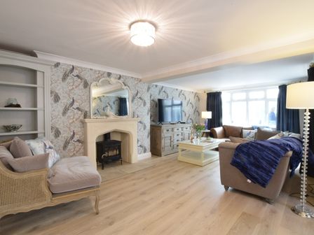 A living room with sofas a coffee table a fireplace and a television at Napier House Southwold