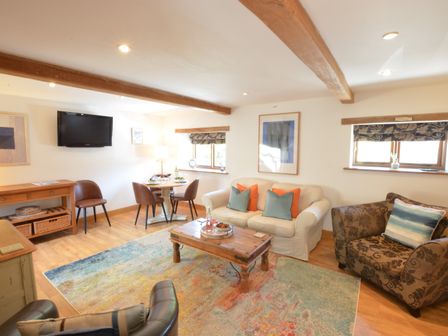 A living room with sofas a coffee table a dining table with chairs and a wall-mounted TV at May Barn Ixworth in Bury St Edmunds