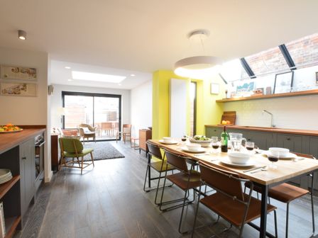 A kitchen and dining area with a wooden table set for six people and a seating area with chairs and a rug at 37 Stradbroke Road Southwold