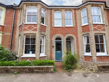 The front facade of a brick house with a blue door and large windows at 14 Dunwich Road Southwold