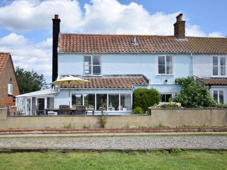 A semi detached house with a tiled roof patio furniture and an umbrella in the garden at 5 Blackshore Southwold