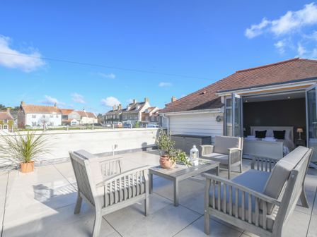 An outdoor patio with seating and a table with plants outside a bedroom at Sea Green Cottage Walberswick