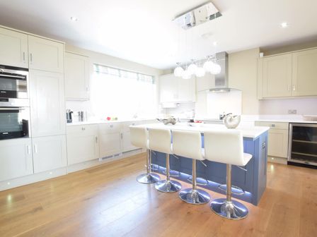 A kitchen with a blue island and white stools at St Marys View Southwold