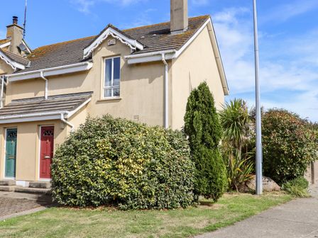 Exterior of a beige semi detached house with two doors and bushes in front at No 1 Mariners Court Rosslare Strand