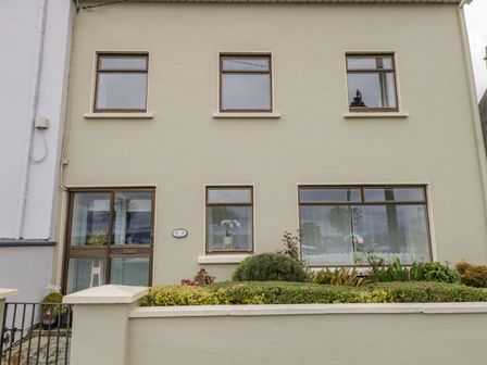 A two-story building with six windows and a glass door with plants in front at Sea Watch House Roundstone County Galway