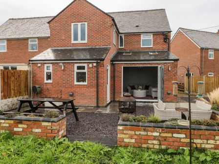 A backyard with patio furniture a fire pit and a brick house at 9 Pilgrims Way in Roch