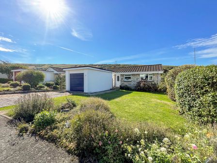 A single-story house with a garage and front garden under a sunny sky at Hill View in West Lulworth