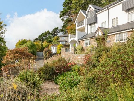 A pathway with plants and shrubs leading to houses on a hillside at 4 St Elmo Court in Salcombe
