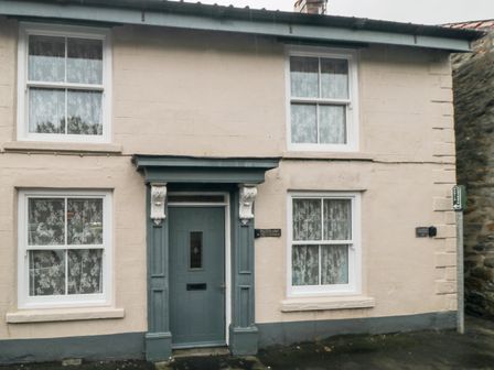 The exterior of a two story house with four windows and a blue door at Crumble's Cottage in Kirkbymoorside