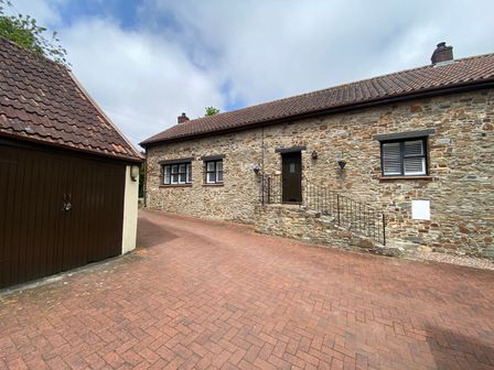 Stone house with three windows a door and steps next to a brown wooden garage at 1 Old Farm Court in Barnstaple