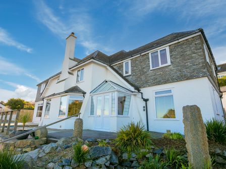 Exterior view of a two-story house with a porch and garden with rocks and plants at Beachcroft in Carbis Bay